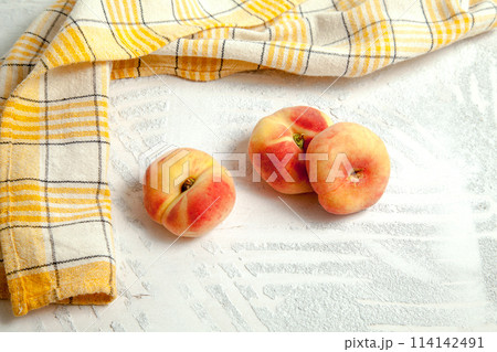 Three saturn peaches or flat peach on white wooden background.. Three saturn peaches or flat peach on white wooden background.. 114142491