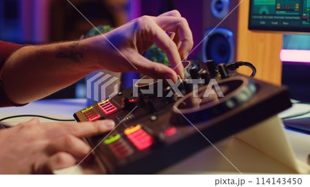 Artist editing sounds on mixing console in home studio, operating professional audio equipment to adjust volume levels on track recordings. Musician works with daw software an pre amp knobs, Camera A. Artist editing sounds on mixing console in home studio, operating professional audio equipment to adjust volume levels on track recordings. Musician works with daw software an pre amp knobs, Camera A. 114143450