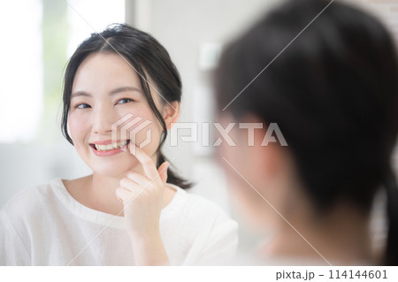鏡を見ながら歯や白さを見るかわいい女性 ホワイトニングなど クローズアップ 鏡を見ながら歯や白さを見るかわいい女性 ホワイトニングなど クローズアップ 114144601