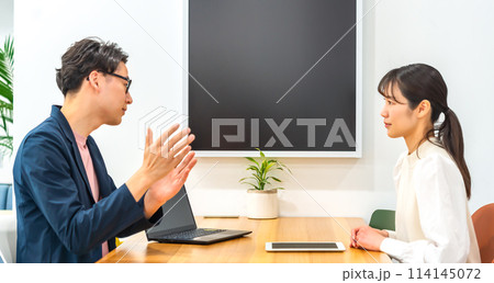 フリーアドレスオフィスでミーティングをするビジネスマンとビジネスウーマン 114145072