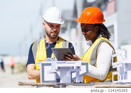 Engineer team discuss and examine about the building plan on blueprint together. Professional engineers working in the construction site. 114145265