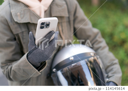 スマホを持つ女性ライダーの手元 114145614