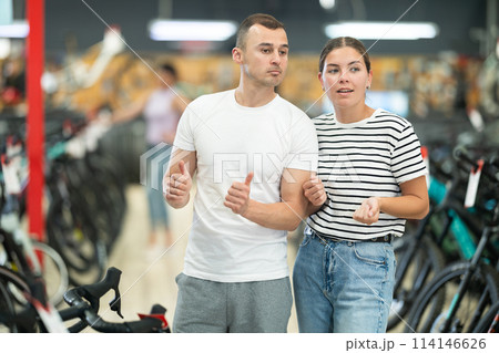 Interested young couple walking through specialized bicycle store Interested young couple walking through specialized bicycle store 114146626