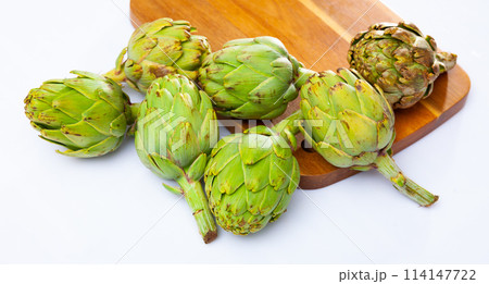 Fresh artichokes on wooden board on white background Fresh artichokes on wooden board on white background 114147722