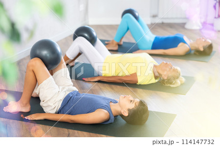 Positive preteen boy practicing lying fitness pose with softball between legs Positive preteen boy practicing lying fitness pose with softball between legs 114147732