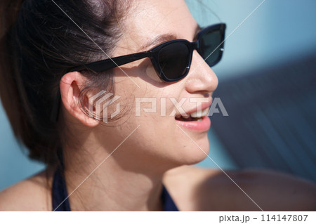 woman pretty wearing swimsuit and sunglasses sitting at swimming pool side from vacation. 114147807