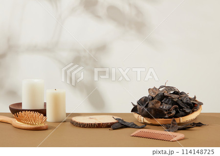 Rustic concepts photo with white background against locust fruits featured on rattan tray, empty wooden podium, candle, hair comb on brown table. Blank space for displaying product Rustic concepts photo with white background against locust fruits featured on rattan tray, empty wooden podium, candle, hair comb on brown table. Blank space for displaying product 114148725