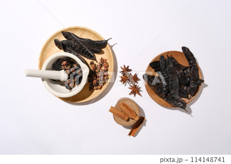 Above view photo at some wooden dishes contains black locust, anise, cinnamon and dried rose buds, white texture. Space for text, suitable for advertising photo 114148741