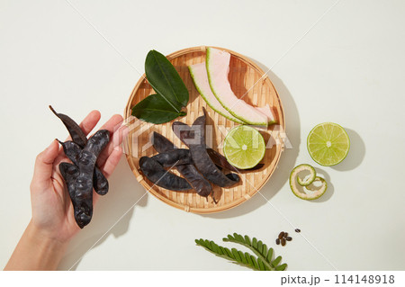 A beautiful hand is holding some black locust, a rattan tray with ingredients for produce manufacturing of haircare. Photo for advertising or branding 114148918