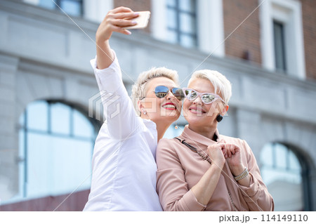 stylish adult business women pose for selfie outside near office building stylish adult business women pose for selfie outside near office building 114149110