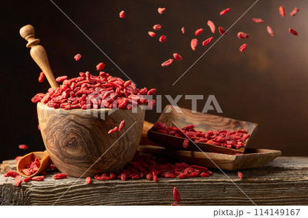 Dried goji berries in wooden bowl on a brown background. 114149167