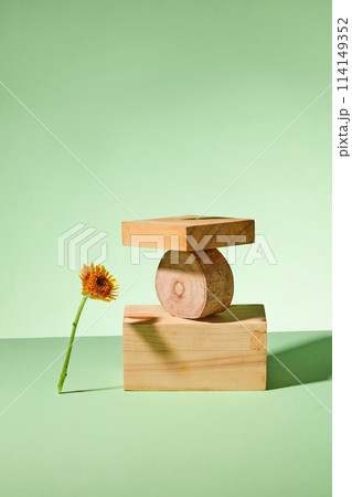 Stack of wooden block decorated on a green background with calendula flower. Minimal scene for advertising cosmetic product of natural ingredient. Front view 114149352