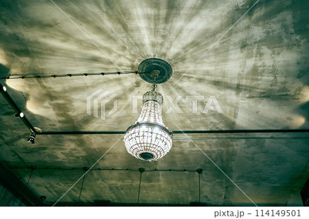 A chandelier with lamps. Light in the interior. The chandelier is made of antique glass. Ceiling with chandelier shadows with space to copy. High quality photo 114149501