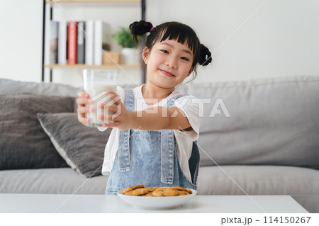 A young girl is holding a glass of milk and a plate of cookies A young girl is holding a glass of milk and a plate of cookies 114150267