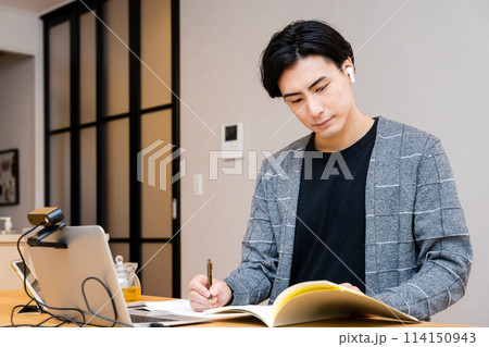 リスキリングのためにリビングで資格と語学と英会話の勉強をする30代の社会人の男性 リスキリングのためにリビングで資格と語学と英会話の勉強をする30代の社会人の男性 114150943