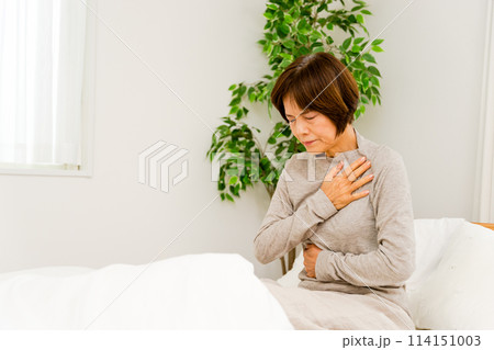 病室で寝起きで胸とお腹が痛む50代から60代のシニアの女性 病室で寝起きで胸とお腹が痛む50代から60代のシニアの女性 114151003