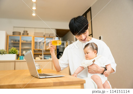 リビングの机で赤ちゃんをあやしながらノートパソコンで仕事をする20代から30代の男性 リビングの机で赤ちゃんをあやしながらノートパソコンで仕事をする20代から30代の男性 114151114