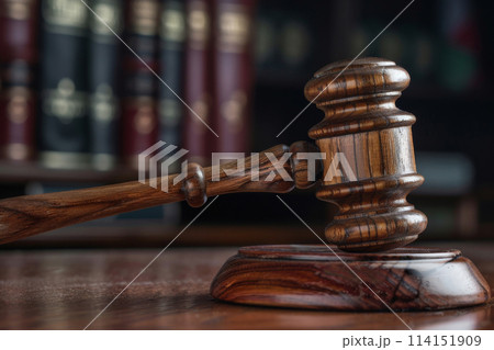 Close-up of a wooden judge's gavel on its sound block, placed on a polished courtroom table, representing the judicial system and justice administration Close-up of a wooden judge's gavel on its sound block, placed on a polished courtroom table, representing the judicial system and justice administration 114151909