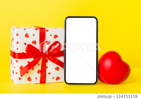 mobile phone with blank screen on colored background with hearts, calendar and gift box, valentine day concept perspertive view flat lay mobile phone with blank screen on colored background with hearts, calendar and gift box, valentine day concept perspertive view flat lay 114153139