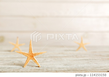 Summer time concept with sea shells or starfish on a table background with copy space for text 114153150