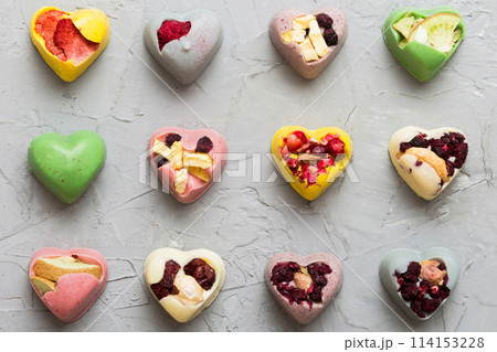 chocolate sweets in the form of a heart with fruits and nuts on a colored background. top view with space for text, holiday concept chocolate sweets in the form of a heart with fruits and nuts on a colored background. top view with space for text, holiday concept 114153228