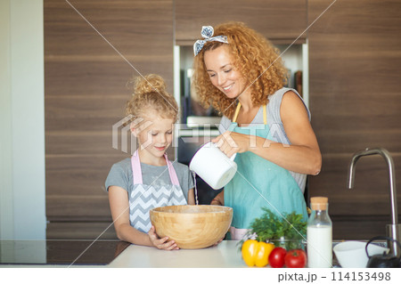 Little daughter helping mother baking in kitchen, family and cooking Little daughter helping mother baking in kitchen, family and cooking 114153498