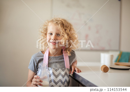 Cute little girl with glass of milk on color background Cute little girl with glass of milk on color background 114153544