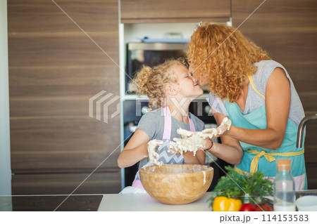 Mother and child daughter girl having fun while making dinner at the kitchen. Mother and child daughter girl having fun while making dinner at the kitchen. 114153583