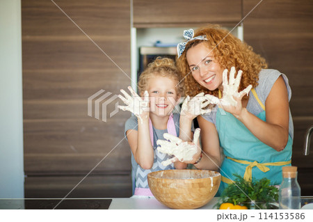 Mother and child daughter girl having fun while making dinner at the kitchen. 114153586