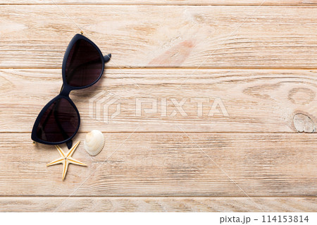 sunglasses with seashell lying on table background. Sunglasses on summer background. Top view flat lay with copy space for text 114153814