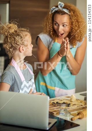 Child and women cutting form for cookie in dough. Happy family and childhood. 114154353