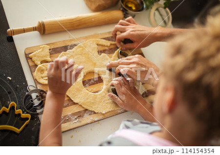 Child and women cutting form for cookie in dough. Happy family and childhood. 114154354