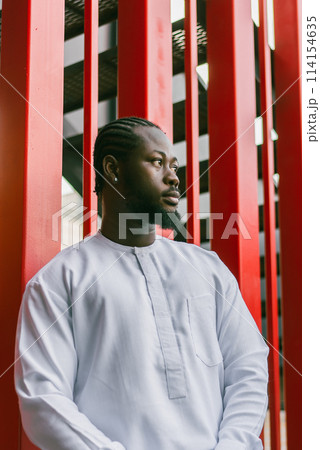 Cheerful male tourist portrait dress in white wear dashiki ethnic smiling at city street or small town background. African American travel model have free time. Millennial generation and gen z people 114154635