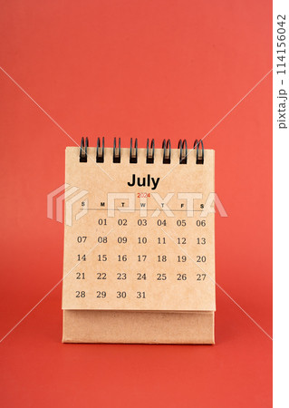 July 2024 white mini desk calendar on red background. July 2024 white mini desk calendar on red background. 114156042