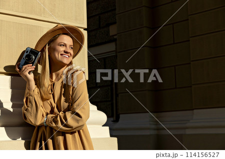 A beautiful girl with a camera on the street. 114156527