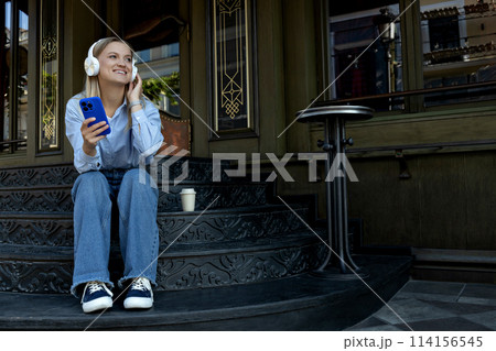 A girl in headphones and with a phone on the street. A girl in headphones and with a phone on the street. 114156545