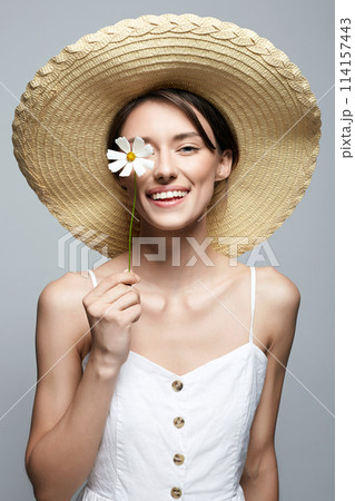 village girl in hat with flower. beautiful smiling young woman with chamomile village girl in hat with flower. beautiful smiling young woman with chamomile 114157443