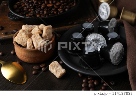 Coffee capsules, coffee beans and cane sugar in bowl on wooden background 114157855