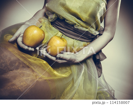 Woman sit in green light dress with apple. Woman sit in green light dress with apple. 114158007