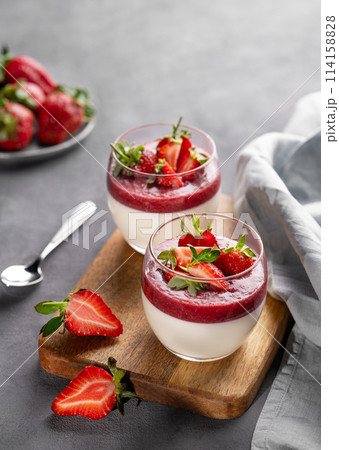 Panna cotta with strawberry and cream in glasses with fresh berries on a wooden board Panna cotta with strawberry and cream in glasses with fresh berries on a wooden board 114158828