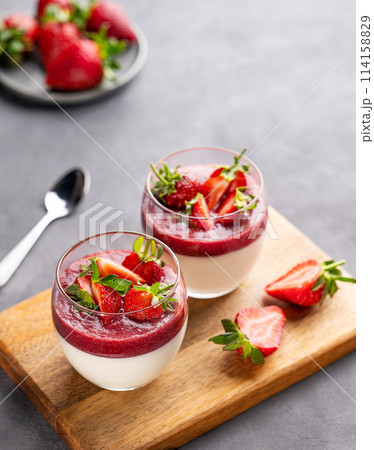 Strawberry and cream panna cotta in glasses with fresh berries on a wooden board Strawberry and cream panna cotta in glasses with fresh berries on a wooden board 114158829
