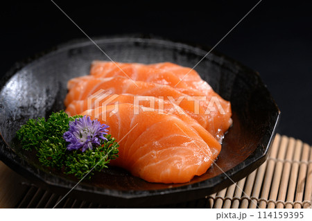 Salmon sashimi on black plate with parsley leaf. Japanese food style Salmon sashimi on black plate with parsley leaf. Japanese food style 114159395