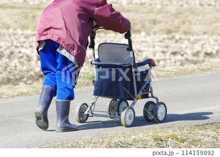 補助車で歩いて畑の農作業に向かう農婦 114159892
