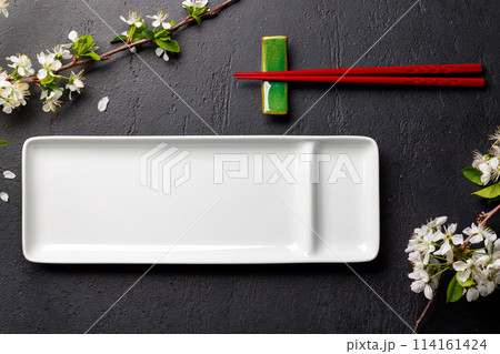 Table adorned with cherry blossom branch and chopsticks, epitomizing Japanese food culture 114161424