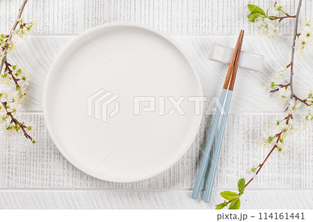 Table adorned with cherry blossom branch and chopsticks, epitomizing Japanese food culture 114161441