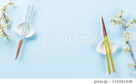 Table adorned with cherry blossom branch and chopsticks, epitomizing Japanese food culture Table adorned with cherry blossom branch and chopsticks, epitomizing Japanese food culture 114161446