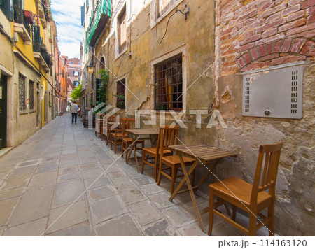 屋外の狭い路地に設置された椅子とテーブル (イタリア、ヴェネツィア) 屋外の狭い路地に設置された椅子とテーブル (イタリア、ヴェネツィア) 114163120