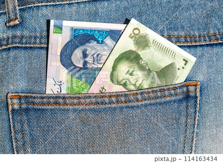 Iranian and Chinese banknotes sticking out of the jeans pocket 114163434