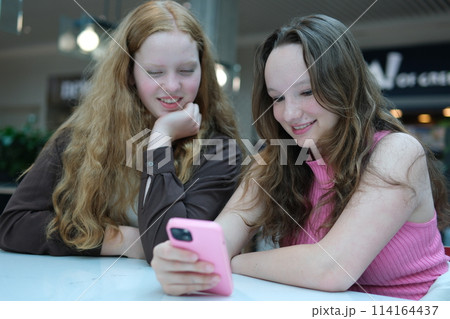 Close up of two young girls looking at smartphone playing mobile games, chatting in social media. High quality photo 114164437