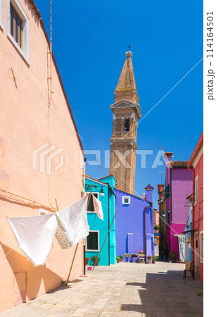 カラフルな建物の背後にそびえる古い教会の尖塔 (イタリア、ブラーノ島) 114164501